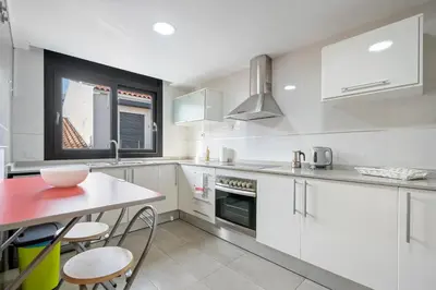 a kitchen with white cabinets and a table and chairs at Hauzify I Apartament Ponent in Pineda de Mar