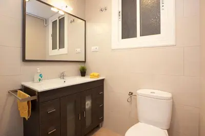 a bathroom with a toilet and a sink and a mirror at Enjoy Apartments VP Camp Nou 2 in Barcelona