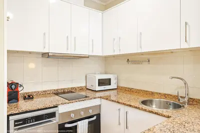 a kitchen with white cabinets and a sink and a microwave at Flateli Pelayo H6 in Barcelona