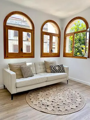 a white couch in a living room with three windows at Historic House at Can Quintana by Casa de Elena in Pineda de Mar