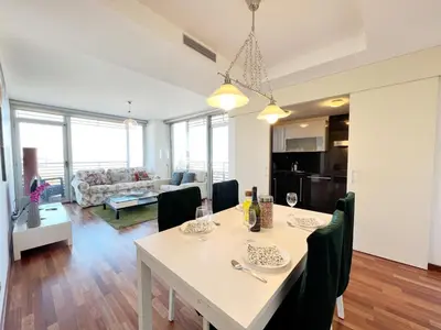 a dining room and living room with a table and chairs at Forum Playa and Pool Barcelona in Barcelona
