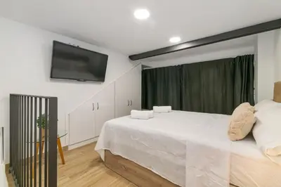 a bedroom with a white bed and a flat screen tv at Nice Central Loft in Vilanova i la Geltrú