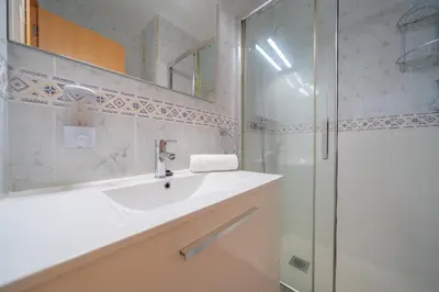 a white bathroom with a sink and a shower at HomeHolidaysRentals Estrella - Costa Barcelona in Pineda de Mar