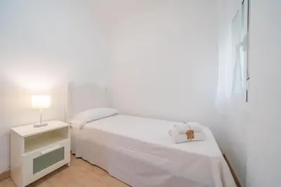 a white bedroom with a bed and a lamp at HomeHolidaysRentals Estrella - Costa Barcelona in Pineda de Mar