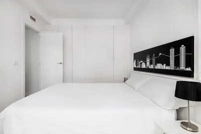 a white bedroom with a white bed with a picture on the wall at La Mejor Zona de Barcelona in Barcelona