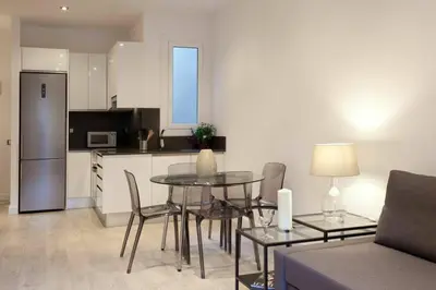 a living room with a table and chairs and a kitchen at Bed&BCN Enamorats in Barcelona