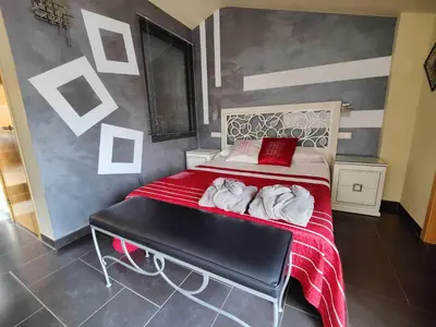a bedroom with a bed with red sheets and a bench at Hostal Manel in Pineda de Mar