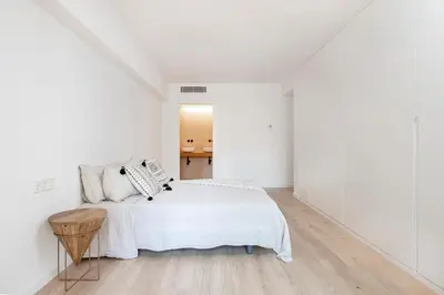 a white bedroom with a bed and a table at Luxury apartment in Barcelona City Center in Barcelona