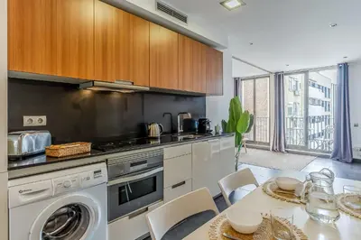 a kitchen with a washing machine and a table with chairs at 1802 - AB Poblenou Comfort in Barcelona