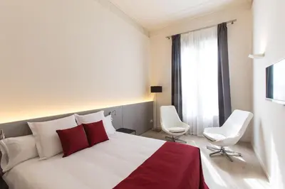 a bedroom with a white bed and two white chairs at Izaila Plaza Catalunya in Barcelona