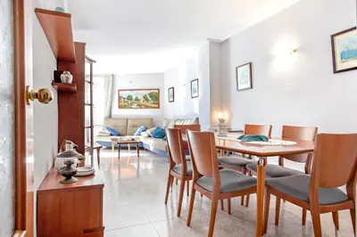 a living room with a table and chairs and a couch at Fantástico apartamento en la playa. A/A y vistas in Pineda de Mar
