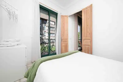 a white bedroom with a bed and a window at Apartamento moderno en Sant Antoni in Barcelona