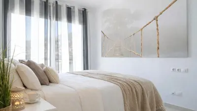 a bedroom with a white bed with a bridge picture on the wall at Tranquil Duplex Sitges, sea views, private parking, terrace in Sitges