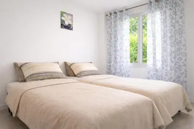 two beds in a white bedroom with a window at Tranquil Duplex Sitges, sea views, private parking, terrace in Sitges