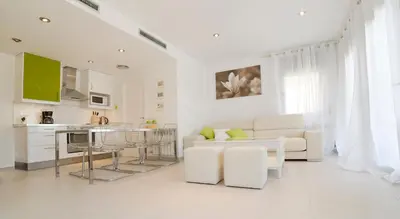 a white living room with a couch and a table at Tranquil Duplex Sitges, sea views, private parking, terrace in Sitges