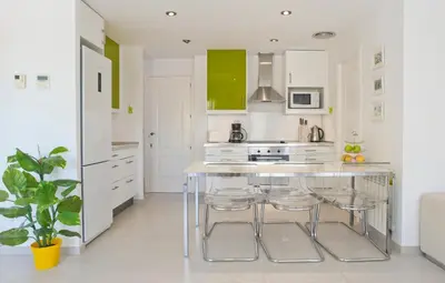 a kitchen with white cabinets and a island with stools at Tranquil Duplex Sitges, sea views, private parking, terrace in Sitges