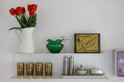 a shelf with a vase of red tulips and a clock at The Patio Barcelona in Barcelona