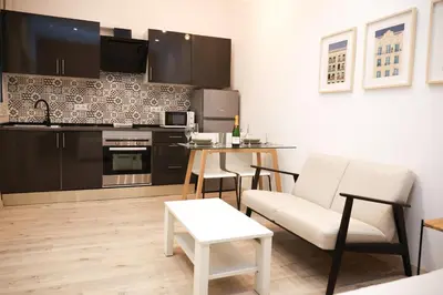 a living room with a table and a kitchen at Cozy near the Barcelona Camp Nou Stadium in Barcelona