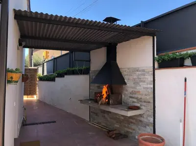 an outdoor kitchen with a fireplace and a stove at CASA CENTRO DEL PUEBLO CON PISCINA PRIVADA in Sant Vicenç de Montalt