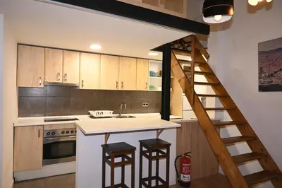 a kitchen with a staircase leading up to a loft at Homenfun Barcelona Vallcarca in Barcelona