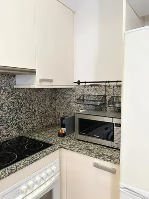 a kitchen with white cabinets and a microwave at SC Apartamento céntrico con balcón in Terrassa
