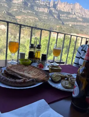 a table with a plate of food and glasses of wine at piso con vistas a la montaña in Monistrol