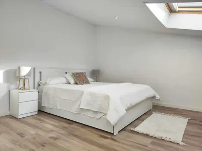 a white bedroom with a white bed and a wooden floor at Mazi Apartments Cuba in Mataró