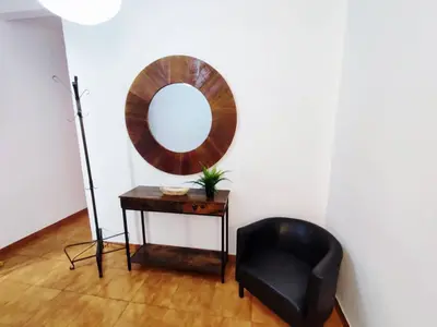 a mirror on a wall next to a black chair at Amplio apartamento con terraza in Hospitalet de Llobregat