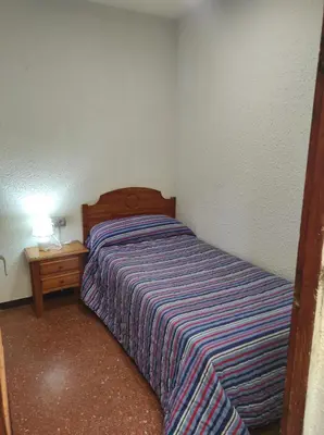 a small bedroom with a bed and a night stand at Apartamentos Can Bruguera 4 in Mataró