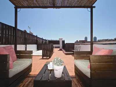a patio with couches and a table on a roof at Sunny Rooftop Apartment in Barcelona