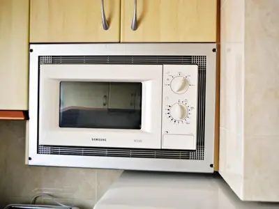 a microwave oven hanging from a wall in a kitchen at AFRODITA Casa con dos apartamentos independientes in Pineda de Mar