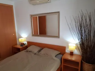 a bedroom with a bed with two lamps and a mirror at SITGES WELCOM HOME a summer flat in the heart of the village Sitges in Sitges