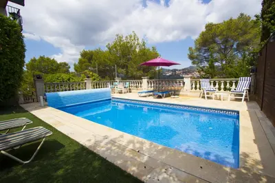 a swimming pool with two chairs and an umbrella at Catalunya Casas Private paradise - hop, skipjump to Barcelona! in Cervelló