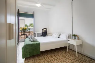 a bedroom with a white bed and a green blanket at BBarcelona Sants Flat in Barcelona