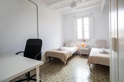 a room with two beds and a table and a chair at BBarcelona Sants Flat in Barcelona