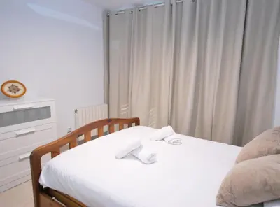 a bedroom with a bed with white sheets and a window at Gaudi Contemporani in Mataró
