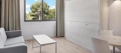 a living room with a couch and a table and a window at B&B HOTEL Barcelona Sant Cugat in Sant Cugat del Vallès