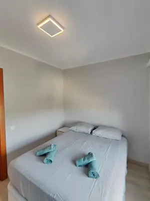 a white bed with two blue pillows on it at Family apartment Besos in Sant Adria de Besos
