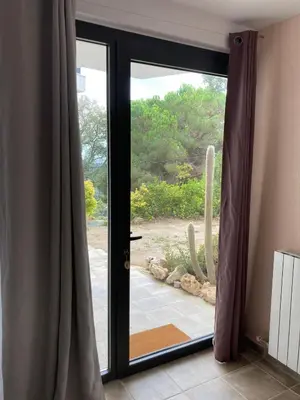 a sliding glass door with a view of a cactus at Casa con vista y jardín, a 20' de la playa in Sant Cebrià de Vallalta