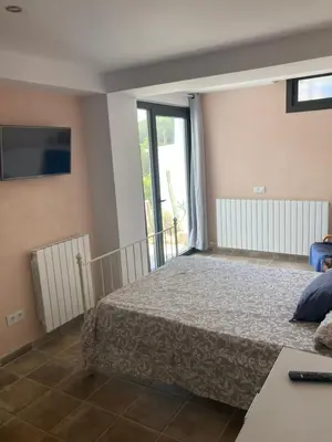 a bedroom with a bed and a large window at Casa con vista y jardín, a 20' de la playa in Sant Cebrià de Vallalta