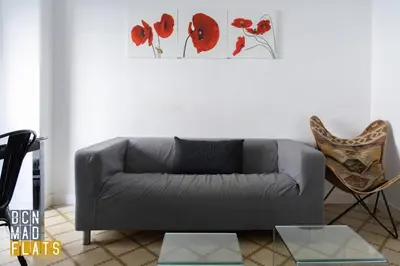 a living room with a gray couch and red flowers on the wall at Bcn - Sagrada Familia in Barcelona