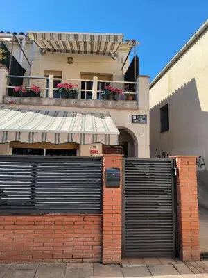 a gate in front of a building with flowers at La casita de Pe Beach in Premiá de Mar