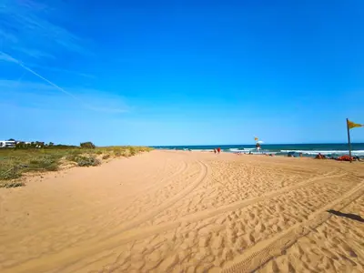 a sandy beach with people flying a kite at Apartamento loft en Castelldefels junto la playa in Castelldefels
