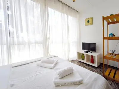 a bedroom with a white bed and a television at Apartamento loft en Castelldefels junto la playa in Castelldefels