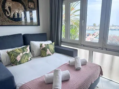 a living room with a couch with towels on a bed at Sitges Port View Apartment by Hello Homes Sitges in Sitges