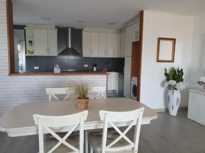 a kitchen with a white table and white chairs at Casa con gran jardín y unas preciosas vistas in Teià