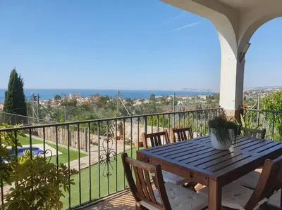 a wooden table and chairs on a balcony with a view at Casa con gran jardín y unas preciosas vistas in Teià