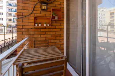 a wooden bench sitting on the side of a balcony at Sunny Beachside Haven 2 BD in the Marina District in Barcelona