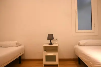 a room with two beds and a lamp on a night stand at Homenfun Barcelona Paseo de Gracia in Barcelona