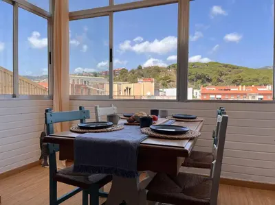 a dining room table with chairs and a view of the city at Apartamento “La Caleta” in Calella